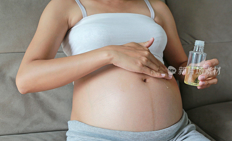 一名孕妇在腹部涂抹妊娠纹霜。
