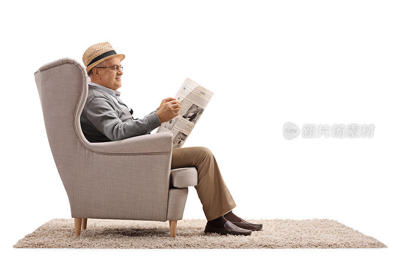 一个成熟的男人坐在扶手椅上看报纸