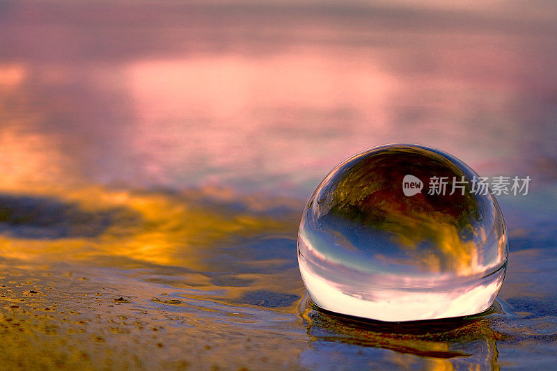夕阳映在沙滩上的玻璃球里