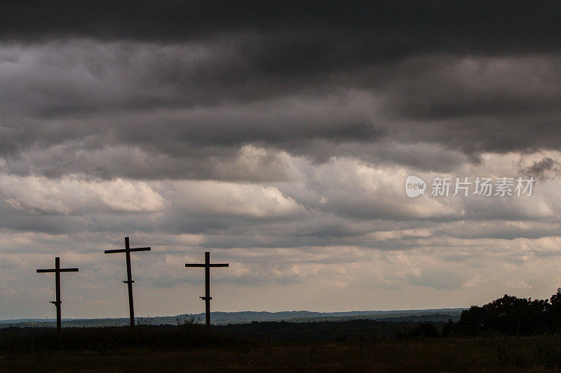三个木制十字架对抗着黑暗的不祥的暴风云