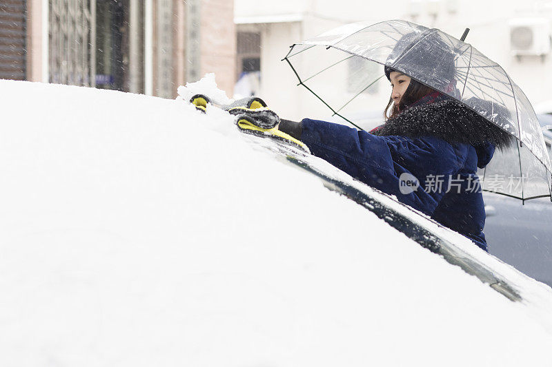 一场暴风雪过后，一名妇女试图清除汽车上的积雪