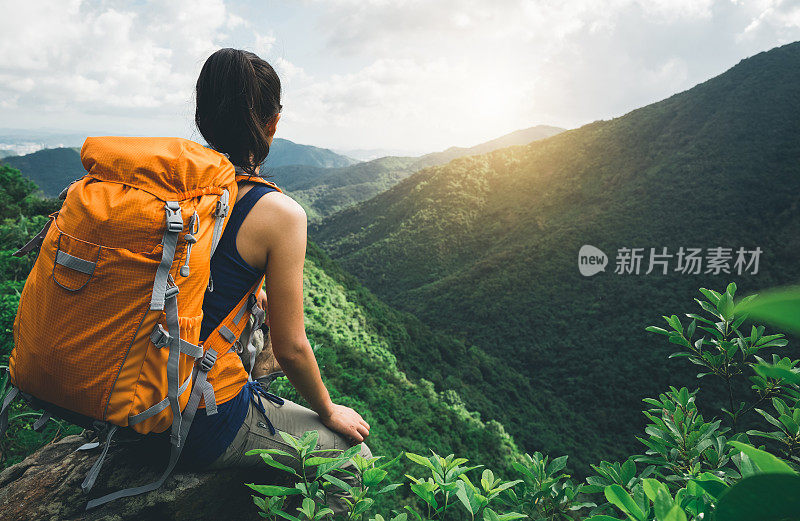 一位年轻的背包客在山顶欣赏风景