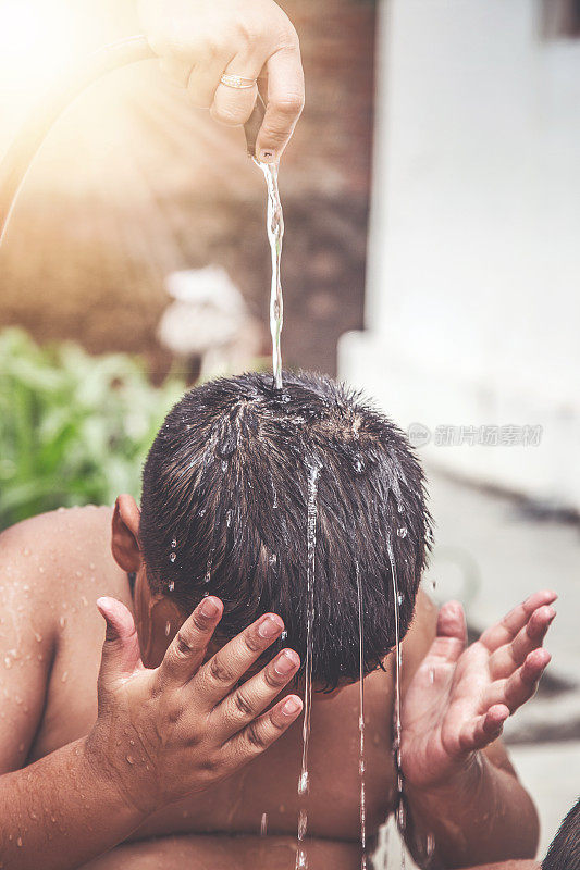 一个年轻的印度男孩在水龙头下洗澡