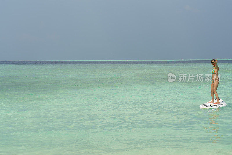 年轻女子在碧绿的大海上冲浪