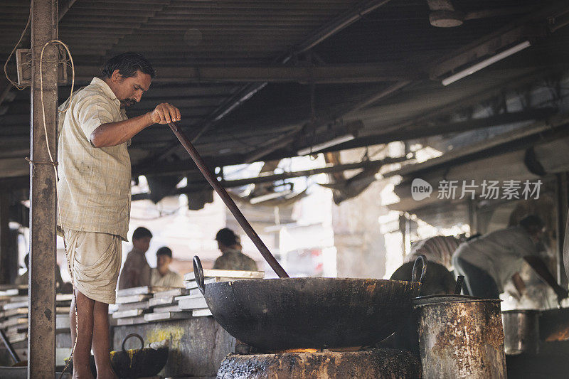 在印度焦特布尔的萨达尔市场，一名男子正在用一个大炒锅做饭