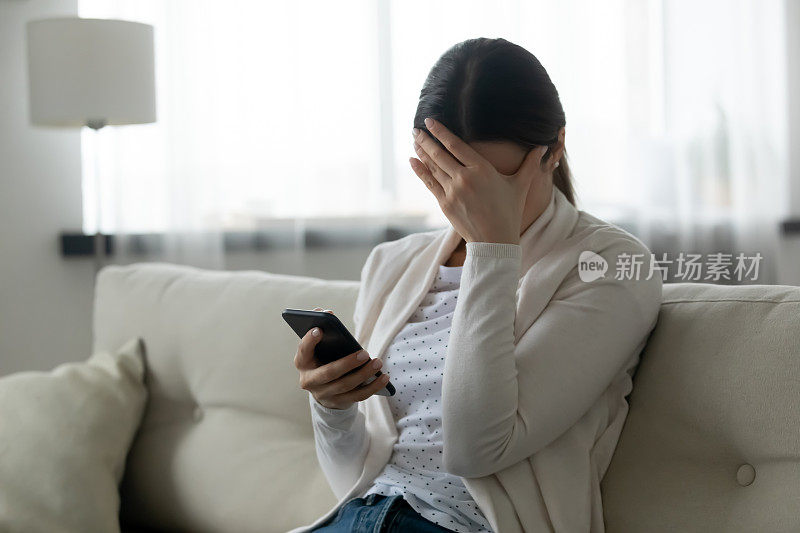 压力大的女性拿着智能手机感觉受到羞辱、网络欺凌