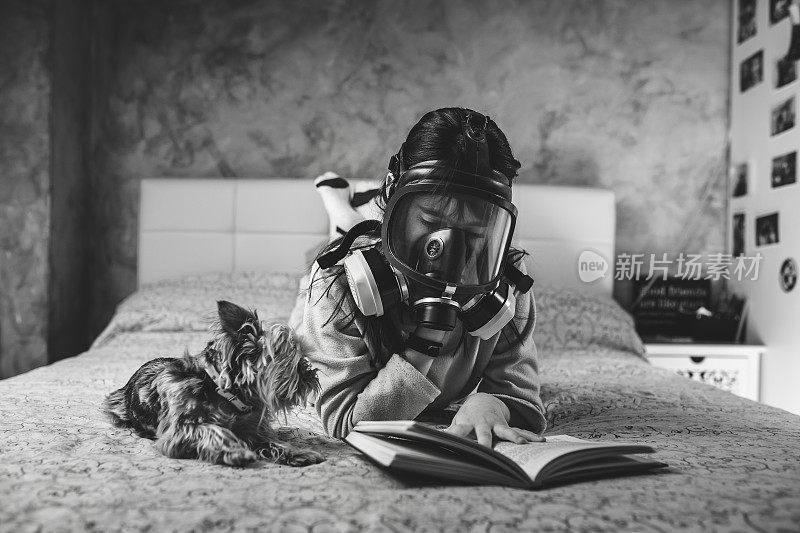 孩子戴着口罩在家看书。