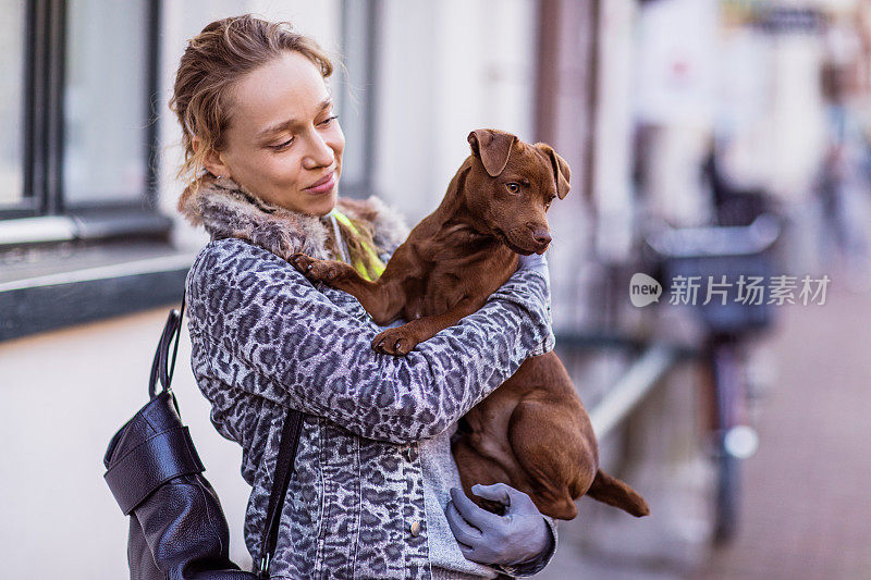 金发女人带着一只小狗走在街上