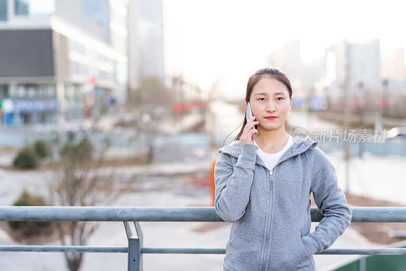 亚洲年轻女子在城市公共广场使用手机