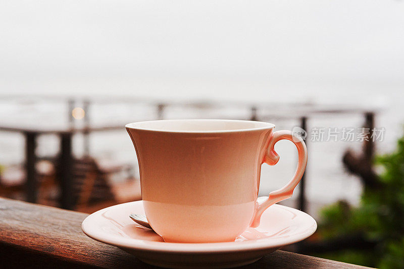 美丽的茶杯放在栏杆上，旁边是阴沉沉的海景