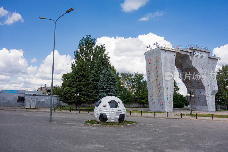 2019年7月，乌克兰哈尔科夫，体育中心和体育场附近的足球装置和室外攀岩墙。夏日城市景观。现代城市建筑装饰通风塔