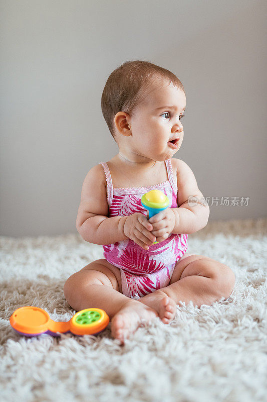 6个月大的女婴坐着拿着玩具