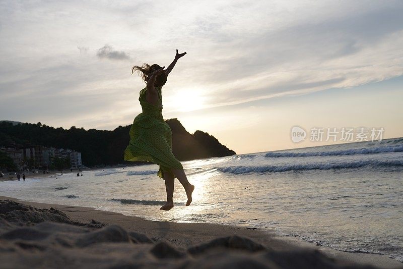 快乐的女人拿着帽子跑着跳着尽情享受海滩度假的生活。