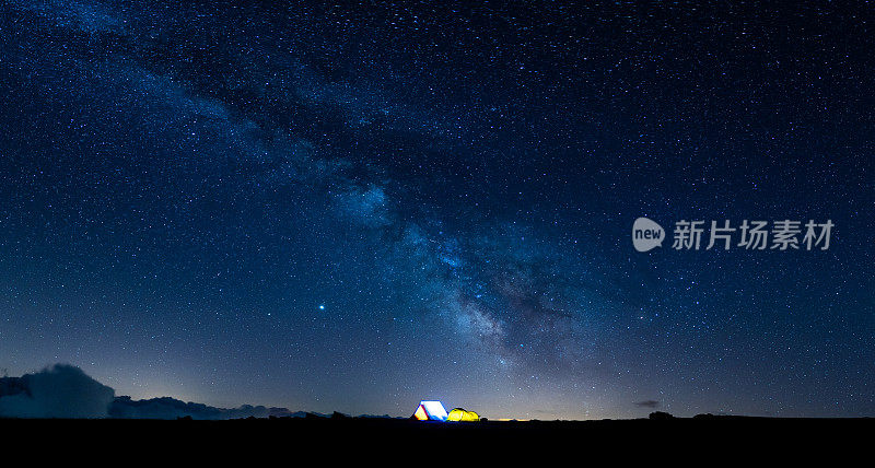 宿营在星空下的山和浩瀚的宇宙。星空下的银河全景，下面是明亮的小帐篷。