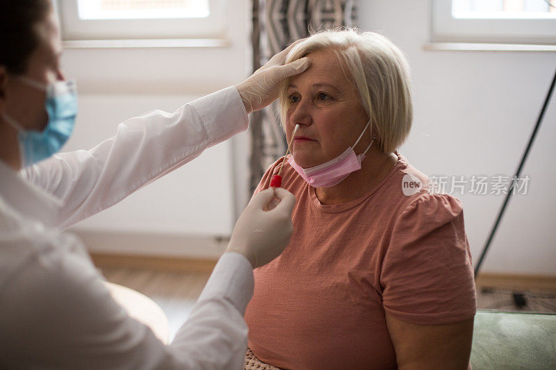 医学专家从一名老年妇女身上提取鼻拭子样本。PCR检测。COVID-19概念。
