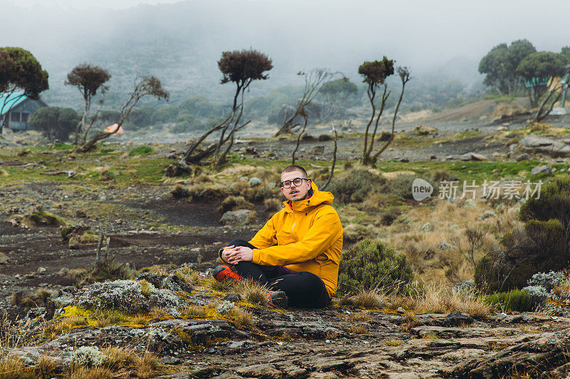 一名年轻的徒步旅行者在前往乞力马扎罗山路上风景优美的营地休息