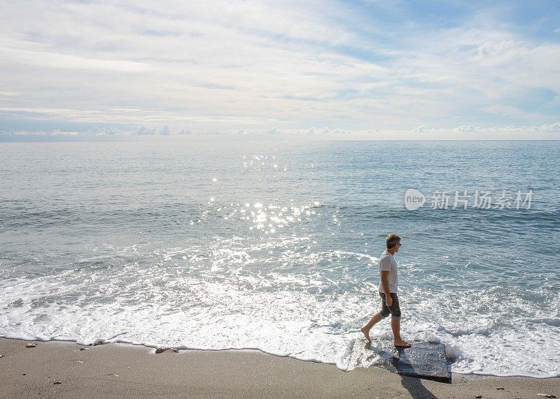 日出时，人们沿着海滩走到水边