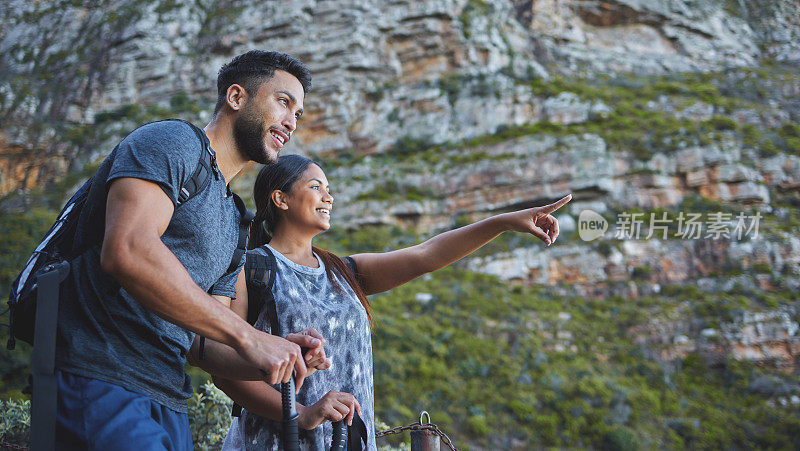 这是一对年轻夫妇在山间徒步旅行时欣赏日落美景的照片