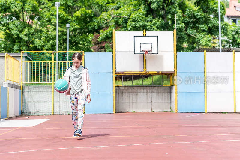 女孩独自在城市篮球场练习篮球