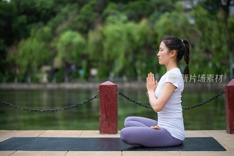 年轻的亚洲妇女在城市公园练习瑜伽