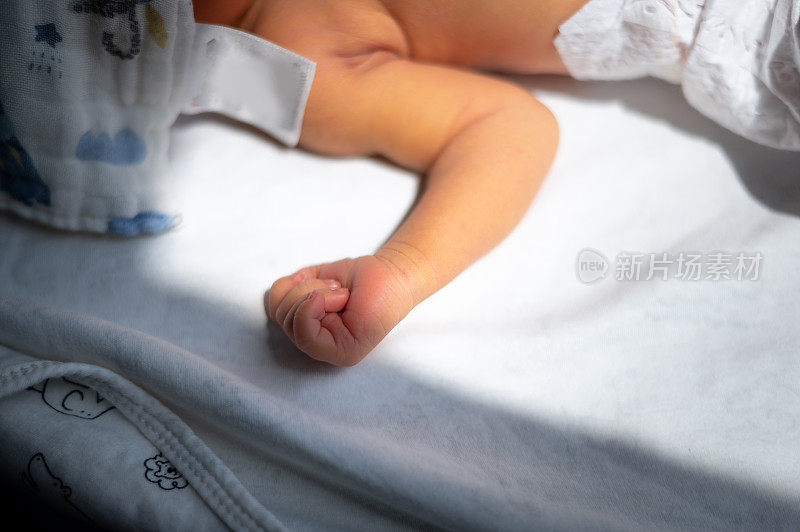 新生儿男婴靠窗吸收阳光，在家裹着毯子治疗黄疸