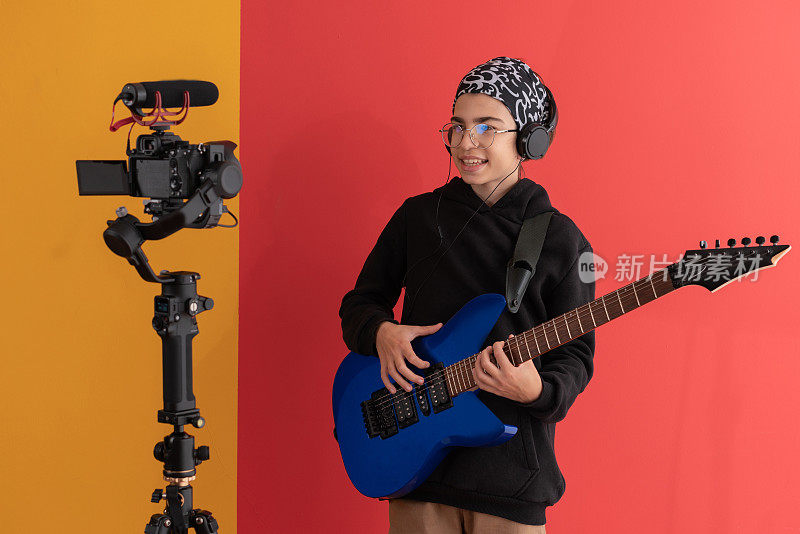 一名年轻的视频博主在摄影棚里在线教弹吉他