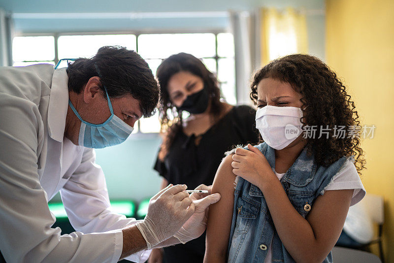 在疫苗接种中心与母亲一起接种疫苗的小女孩