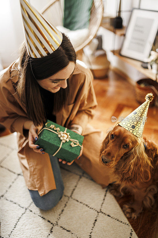 一个女人和她的狗在家里庆祝她的狗的生日。