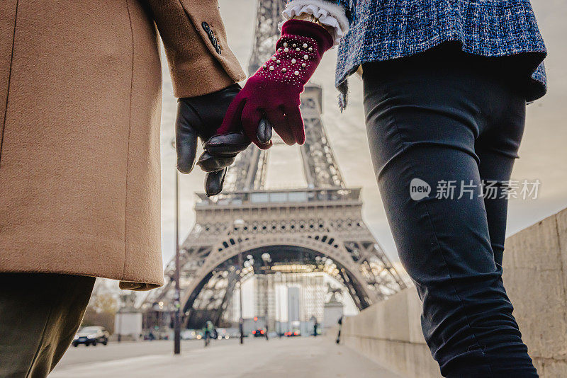 夜晚，巴黎埃菲尔铁塔前，一对情侣牵着手的特写镜头