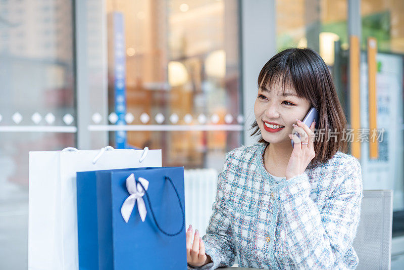 亚洲年轻女子购物后在城市街道使用智能手机