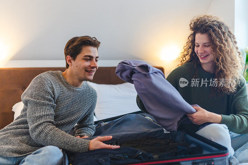 一对漂亮的年轻夫妇正在卧室里收拾行李