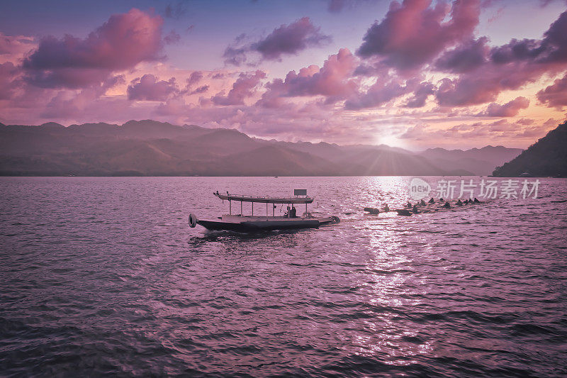 在泰国北碧，人们正乘坐潮湿的木筏在一条大湖中旅行。紫色的天空下