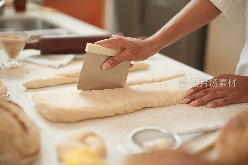 女人在桌子上用糕点切割器切面团的特写。女面包师用一种食谱来烤面包。喜欢在厨房里烘焙和自制食物的人