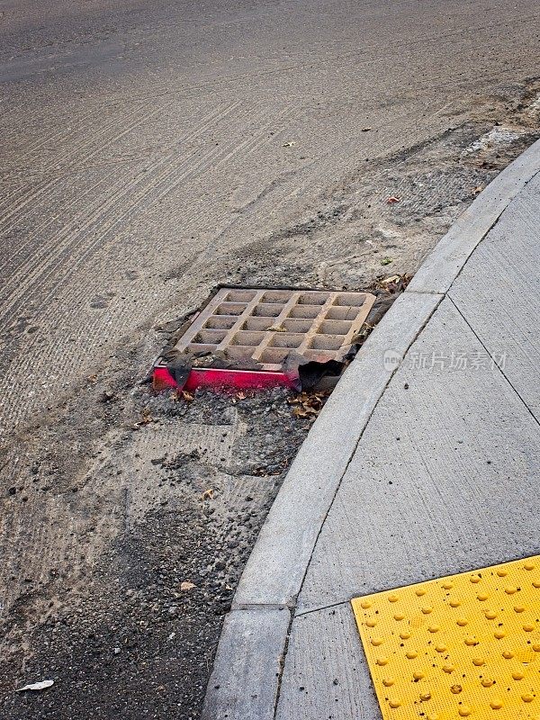 排水格栅作为一个严重的轮胎道路危害，在街道的一边油漆发光读