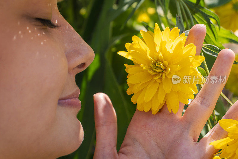 一位年轻女子闻到了雏菊的香味