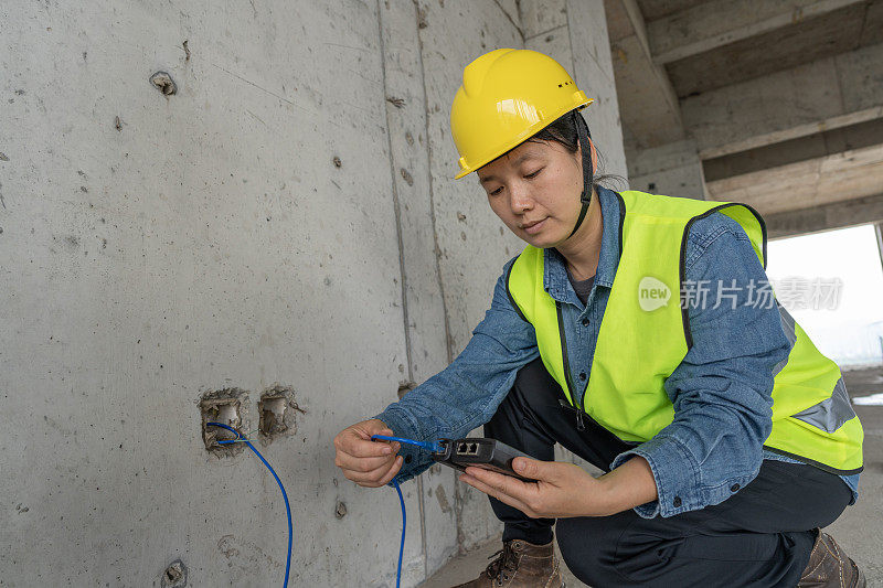 一名女工人正在施工现场铺设控制网线