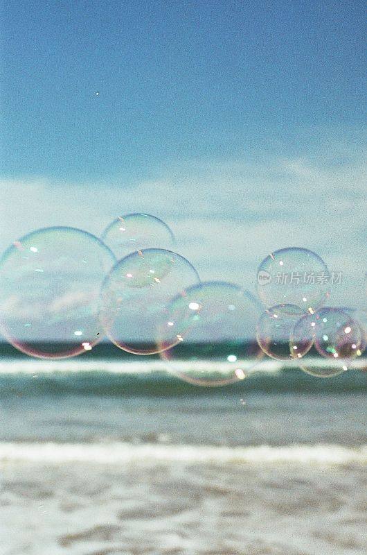 垂直的美丽透明的肥皂泡与泡沫的海浪在模糊的背景