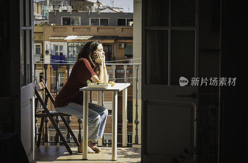 年轻放松的女子吃完饭后在阳台上晒日光浴