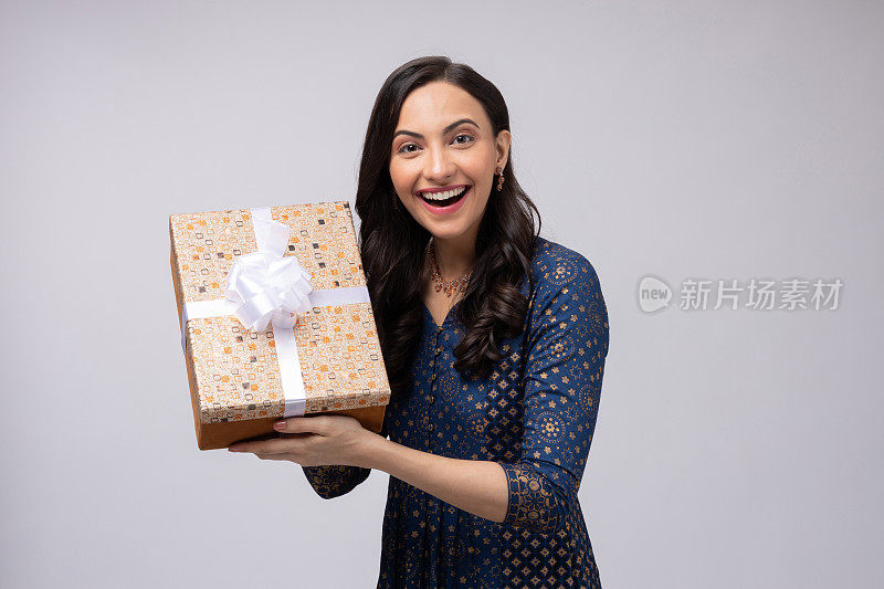 美丽的印度妇女穿着传统服装，拿着礼盒庆祝排灯节，孤立在白色背景的股票照片