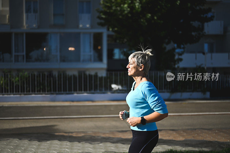 一个成熟的女人早上在城市街道上慢跑的侧面肖像。