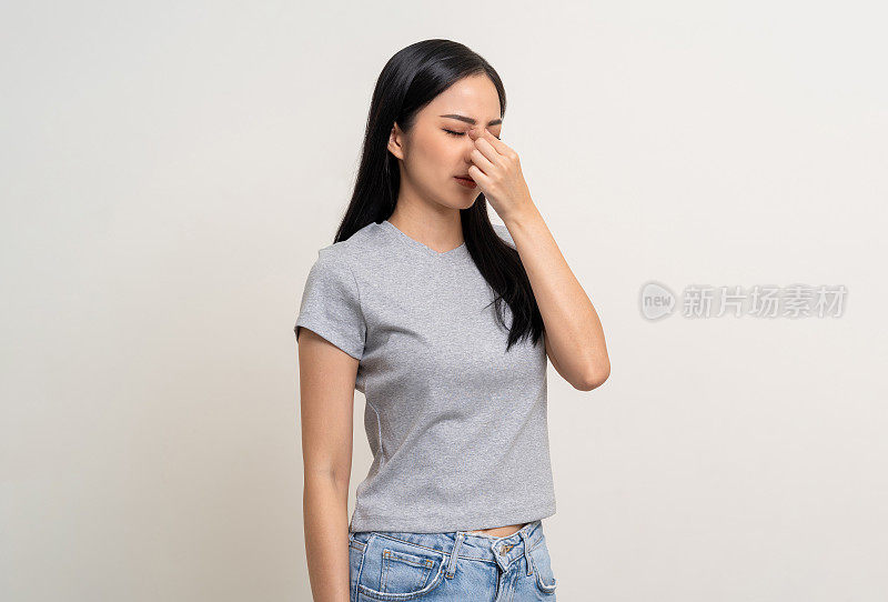 年轻的亚洲美女手揉眼睛她感到沮丧压力头痛工作累了站在孤立的白色背景她有不健康的问题。