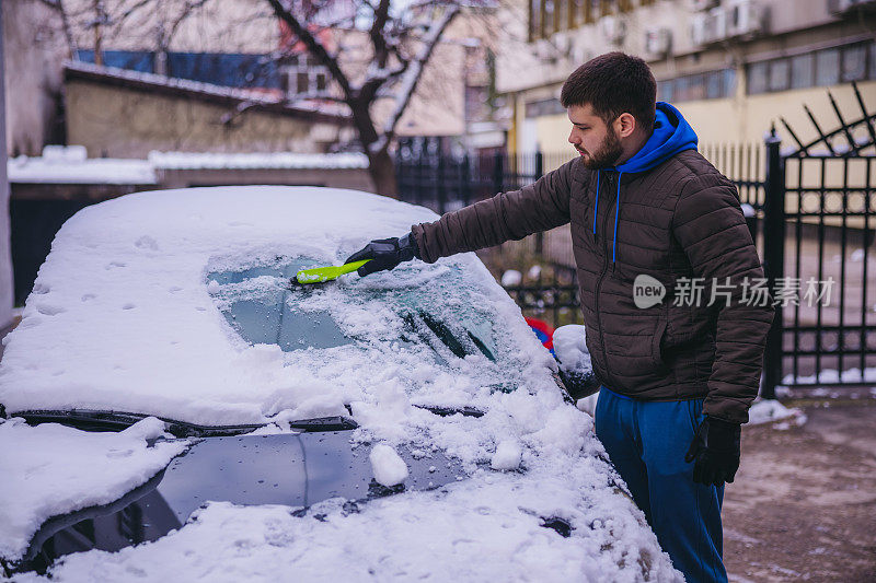 年轻人正在清除汽车上的积雪