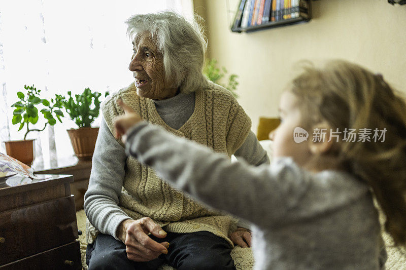 曾祖母在家里和蹒跚学步的孩子玩耍。