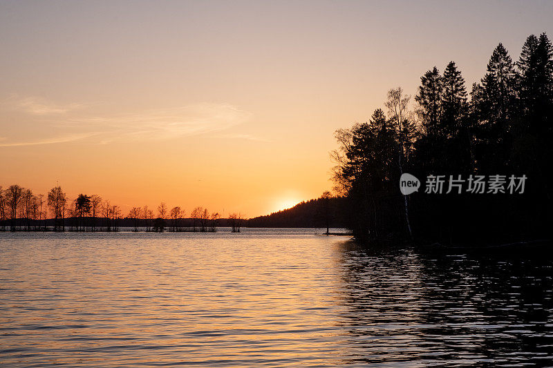 湖上的夕阳，傍晚的天空是橘黄色的。海岸线。