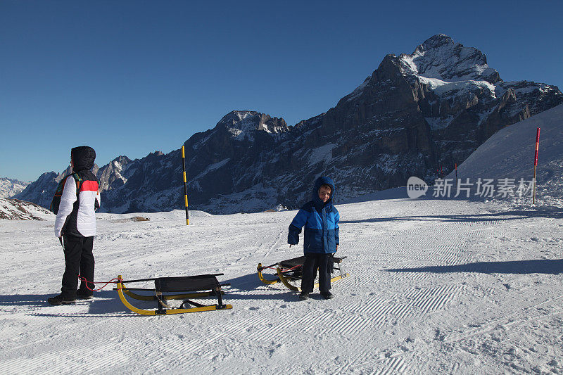 男孩们玩雪橇冬季运动，在瑞士阿尔卑斯山滑雪