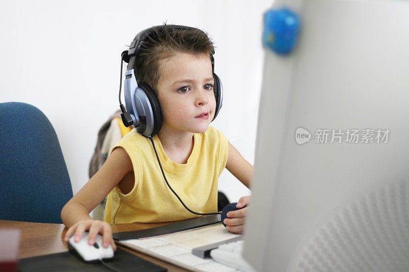 男孩戴着大耳机玩电脑