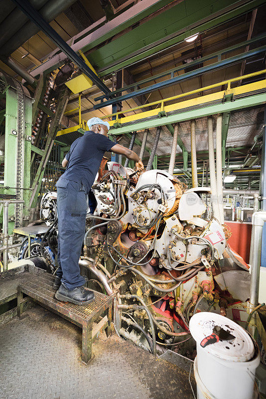工厂工人在检查铝罐加工厂的机器