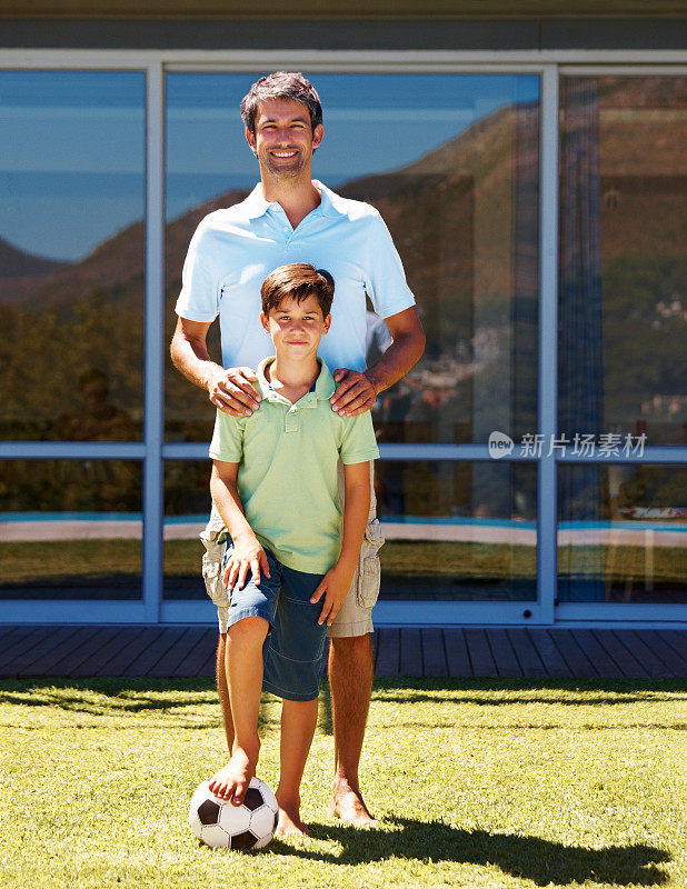 小男孩和他爸爸在后院踢足球