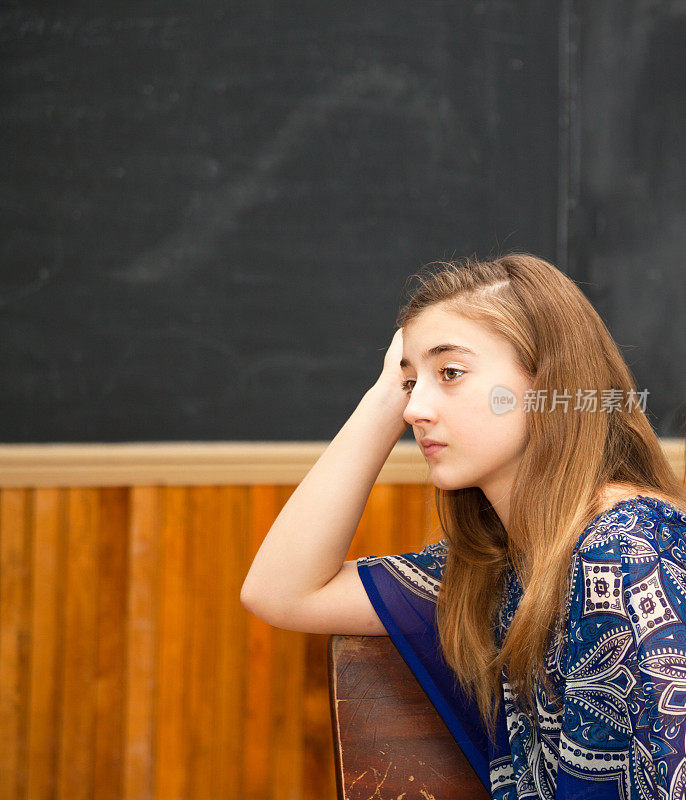 肖像的喜怒无常的少年在复古老教室与黑板