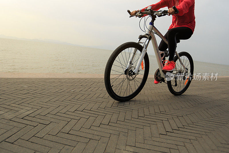 一个年轻的女人在海边骑自行车
